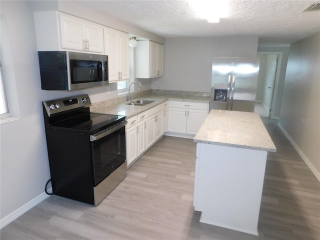 4417 Kohler St, New Port Richey, FL 34652 - kitchen featuring stainless steel appliances, a sink, a center island, light wood-type flooring, and a textured ceiling