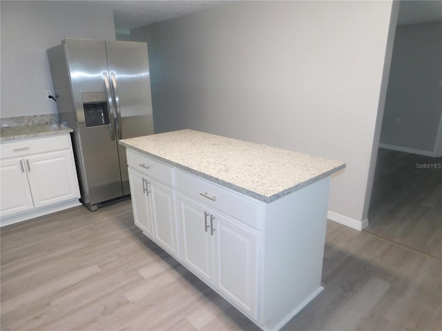 4417 Kohler St, New Port Richey, FL 34652 - kitchen with stainless steel fridge with ice dispenser, light wood-style flooring, white cabinets, and a center island