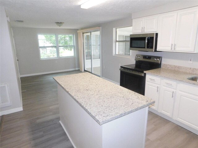 4417 Kohler St, New Port Richey, FL 34652 - kitchen featuring stainless steel microwave, range with electric stovetop, light wood-style floors, light stone countertops, and a textured ceiling