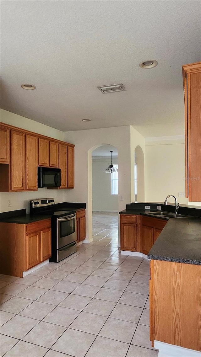 221 Fairmont Dr, Spring Hill, FL 34609 - kitchen with stainless steel electric range oven, black microwave, arched walkways, brown cabinets, and a textured ceiling
