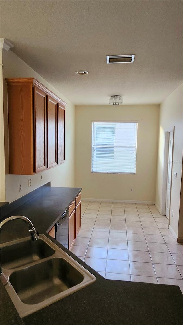 221 Fairmont Dr, Spring Hill, FL 34609 - kitchen with dark countertops, dishwashing machine, brown cabinets, light tile patterned floors, and a textured ceiling