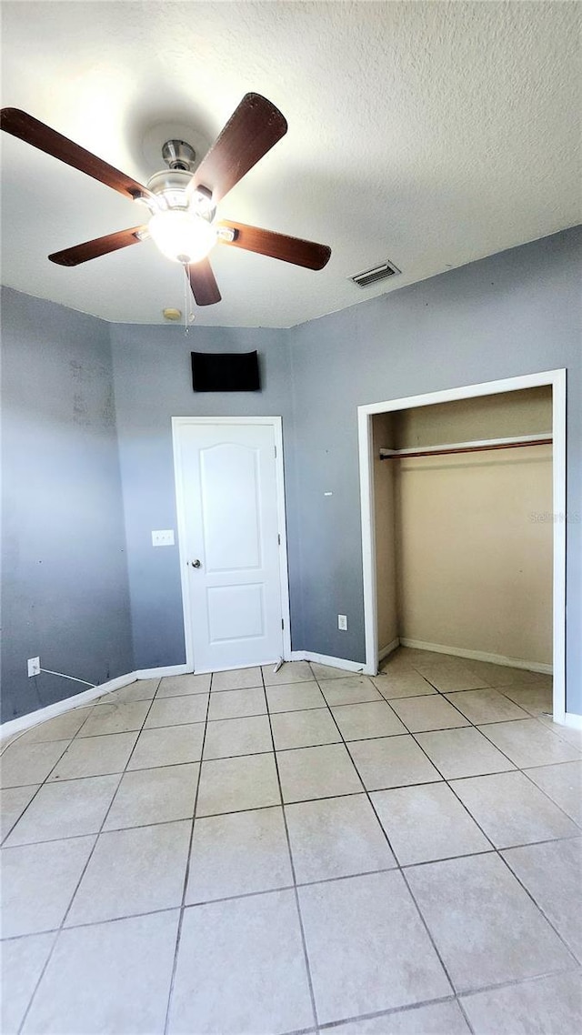 221 Fairmont Dr, Spring Hill, FL 34609 - unfurnished bedroom with a closet, light tile patterned floors, a textured ceiling, and a ceiling fan