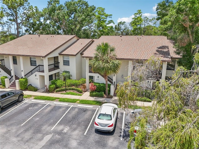 4735 Winslow Beacon Unit 14, Sarasota, FL 34235 - view of front facade featuring stucco siding, stairs, uncovered parking, and a shingled roof