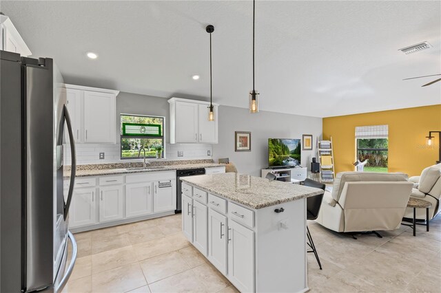 12004 Legacy Bright St, Riverview, FL 33578 - kitchen with stainless steel appliances, open floor plan, tasteful backsplash, a kitchen island, and white cabinetry