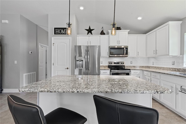 12004 Legacy Bright St, Riverview, FL 33578 - kitchen featuring stainless steel appliances, lofted ceiling, tasteful backsplash, white cabinets, and a kitchen bar