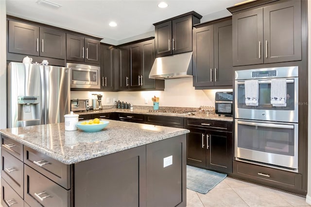 26972 Evergreen Chase Dr, Wesley Chapel, FL 33544 - kitchen featuring stainless steel appliances, under cabinet range hood, a kitchen island, light stone counters, and light tile patterned floors