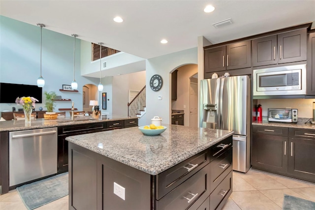 26972 Evergreen Chase Dr, Wesley Chapel, FL 33544 - kitchen with stainless steel appliances, arched walkways, light tile patterned flooring, a kitchen island, and recessed lighting