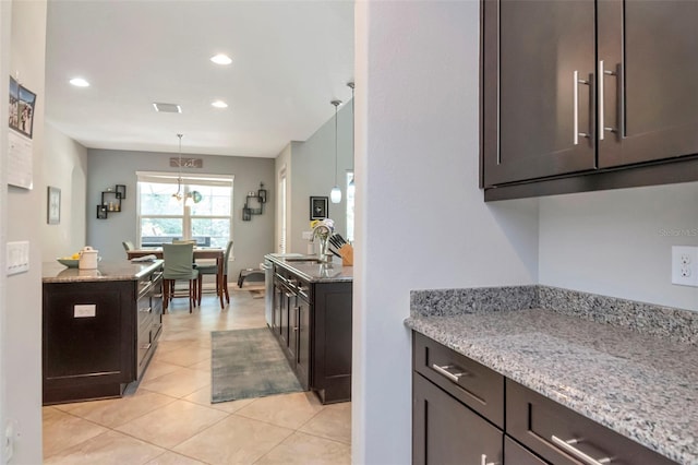 26972 Evergreen Chase Dr, Wesley Chapel, FL 33544 - kitchen featuring light stone countertops, dark brown cabinetry, recessed lighting, and light tile patterned floors
