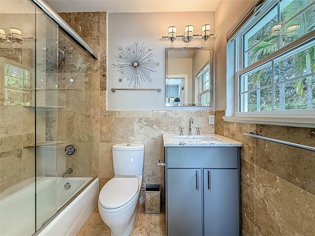 301 23rd Ave NE, Saint Petersburg, FL 33704 - full bathroom featuring tile walls, vanity, enclosed tub / shower combo, and a wainscoted wall