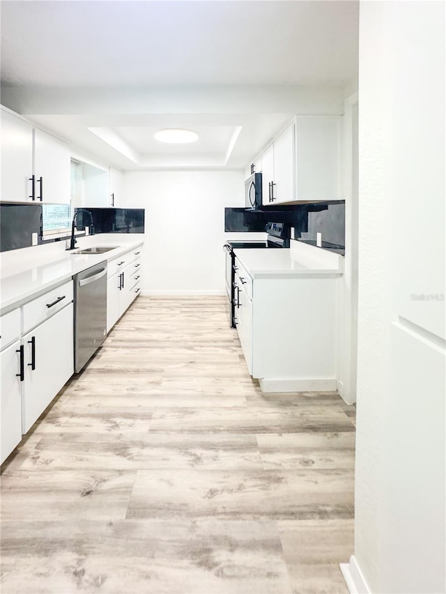 4638 Durney St, New Port Richey, FL 34652 - kitchen featuring stainless steel appliances, a tray ceiling, white cabinets, light countertops, and light wood-type flooring