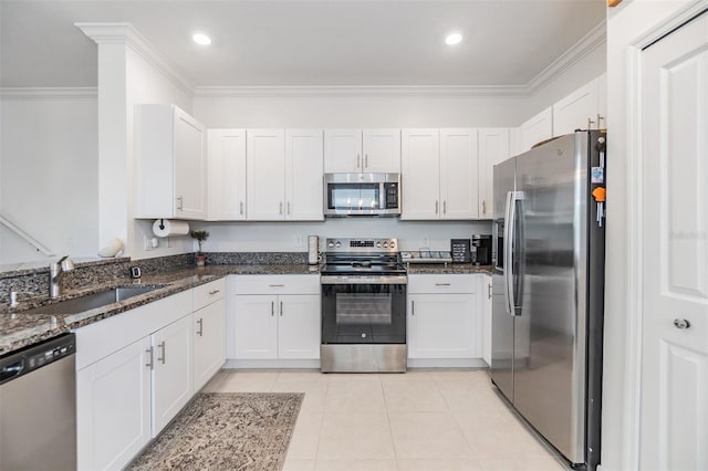 36414 Well Hill Way, Zephyrhills, FL 33541 - kitchen with stainless steel appliances, crown molding, dark stone countertops, light tile patterned floors, and white cabinetry