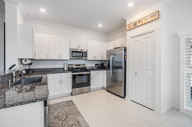 36414 Well Hill Way, Zephyrhills, FL 33541 - kitchen with appliances with stainless steel finishes, dark stone counters, ornamental molding, white cabinetry, and light tile patterned floors
