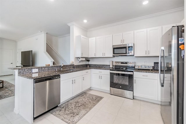 36414 Well Hill Way, Zephyrhills, FL 33541 - kitchen with appliances with stainless steel finishes, ornamental molding, dark stone counters, white cabinetry, and a peninsula