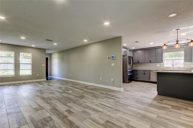 8330 Lafitte Dr, Hudson, FL 34667 - unfurnished living room featuring light wood-style flooring, baseboards, recessed lighting, and a sink