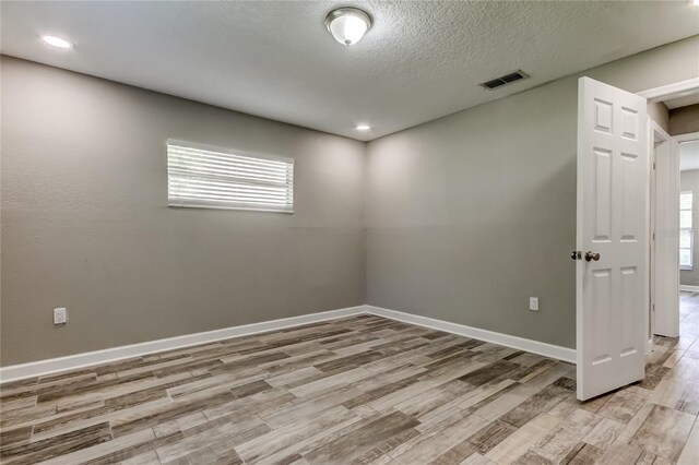 8330 Lafitte Dr, Hudson, FL 34667 - spare room featuring light wood-type flooring, baseboards, and a textured ceiling