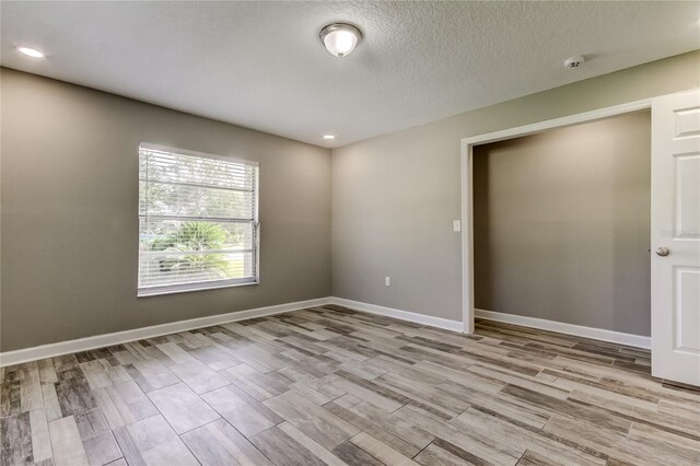 8330 Lafitte Dr, Hudson, FL 34667 - unfurnished room with light wood finished floors, baseboards, recessed lighting, a textured ceiling, and a smoke detector