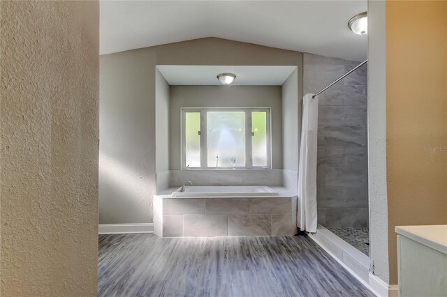 8330 Lafitte Dr, Hudson, FL 34667 - full bath with a bath, a stall shower, a textured wall, wood finished floors, and vaulted ceiling
