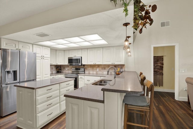 2806 Fairway View Dr, Valrico, FL 33596 - kitchen with appliances with stainless steel finishes, a peninsula, dark wood finished floors, backsplash, and white cabinetry