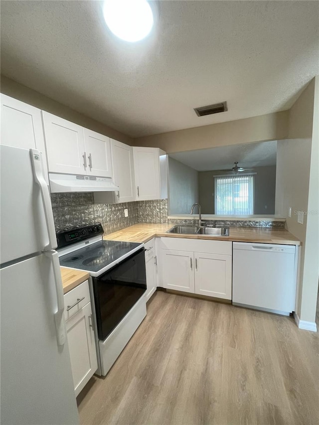 3007 Wainwright Ct, New Port Richey, FL 34655 - kitchen featuring white appliances, a sink, under cabinet range hood, light wood-type flooring, and white cabinets