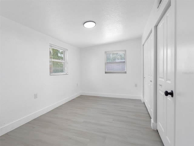 1213 W Camellia Dr, Brandon, FL 33510 - unfurnished bedroom with multiple windows, baseboards, light wood-style flooring, and a textured ceiling
