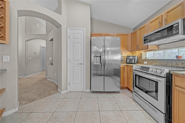 12510 Loquat Way, Tampa, FL 33626 - kitchen featuring appliances with stainless steel finishes, arched walkways, vaulted ceiling, light brown cabinetry, and backsplash