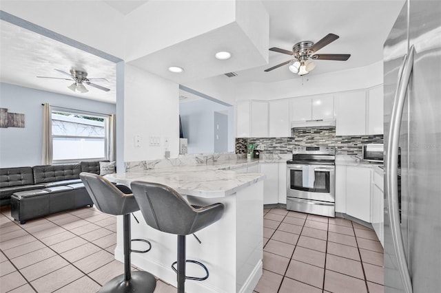 2861 Pinellas Point Dr S, Saint Petersburg, FL 33712 - kitchen featuring appliances with stainless steel finishes, ceiling fan, a peninsula, light tile patterned floors, and a kitchen breakfast bar
