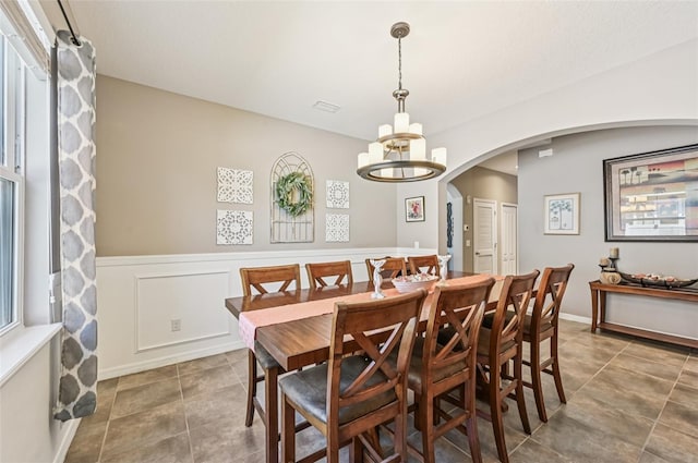 4151 Little Gap Loop, Ellenton, FL 34222 - dining space featuring arched walkways, a chandelier, wainscoting, and tile patterned flooring