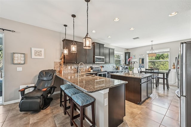 4151 Little Gap Loop, Ellenton, FL 34222 - kitchen with stainless steel appliances, a kitchen island, decorative backsplash, dark brown cabinetry, and stone countertops
