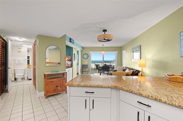 4510 Gulf Blvd Unit 604, St Pete Beach, FL 33706 - kitchen featuring light tile patterned floors, white cabinetry, pendant lighting, and a textured ceiling