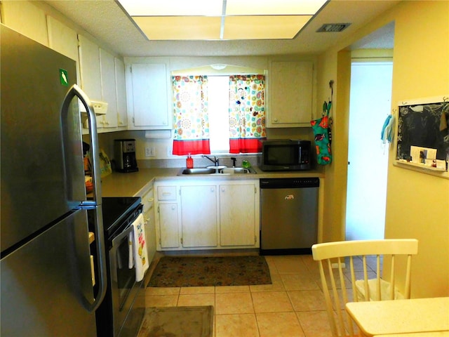 9 Forbes Pl Unit 310, Dunedin, FL 34698 - kitchen with stainless steel appliances, light countertops, light tile patterned floors, and white cabinets