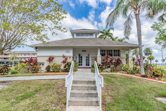 9 Forbes Pl Unit 310, Dunedin, FL 34698 - view of front facade with french doors, a front lawn, stucco siding, and a shingled roof