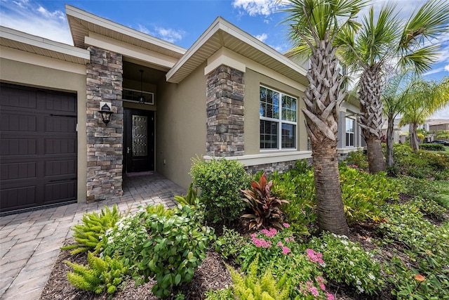 3318 Woodland Brook Way, Wesley Chapel, FL 33543 - view of exterior entry with stucco siding, stone siding, and an attached garage