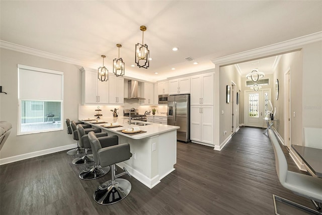 3318 Woodland Brook Way, Wesley Chapel, FL 33543 - kitchen with stainless steel appliances, wall chimney exhaust hood, crown molding, white cabinets, and a breakfast bar