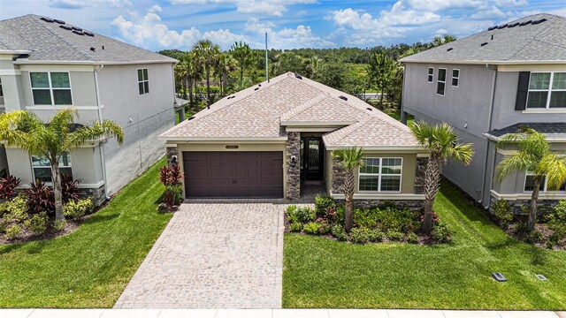 3318 Woodland Brook Way, Wesley Chapel, FL 33543 - view of front of house featuring a garage, driveway, stone siding, and a front yard