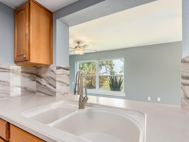 14045 90th Pl, Seminole, FL 33776 - kitchen featuring a sink, light countertops, brown cabinets, a ceiling fan, and decorative backsplash