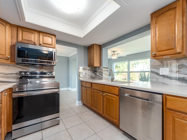 14045 90th Pl, Seminole, FL 33776 - kitchen featuring appliances with stainless steel finishes, a sink, brown cabinetry, tasteful backsplash, and light countertops