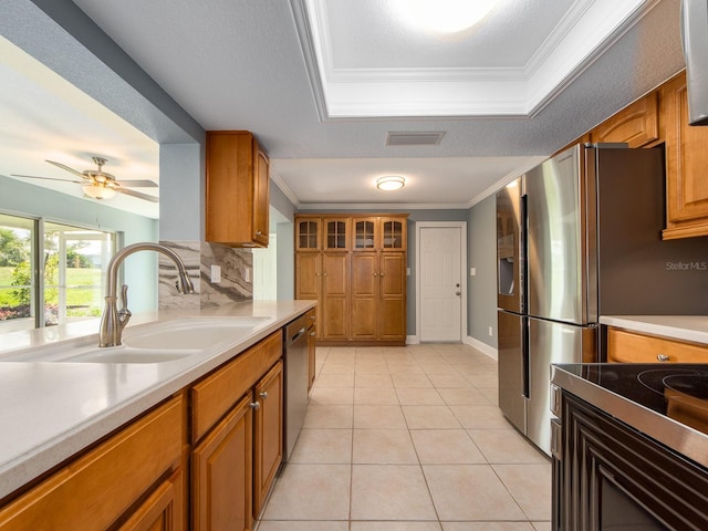 14045 90th Pl, Seminole, FL 33776 - kitchen with a sink, brown cabinets, crown molding, a tray ceiling, and light countertops