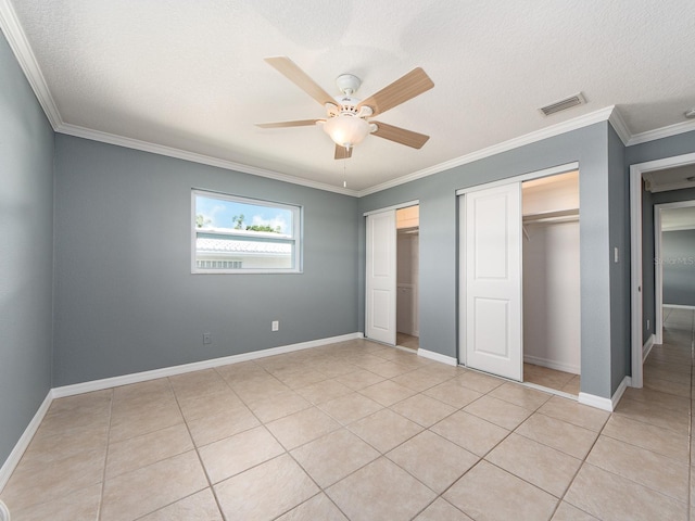 14045 90th Pl, Seminole, FL 33776 - unfurnished bedroom with two closets, crown molding, baseboards, light tile patterned floors, and a ceiling fan