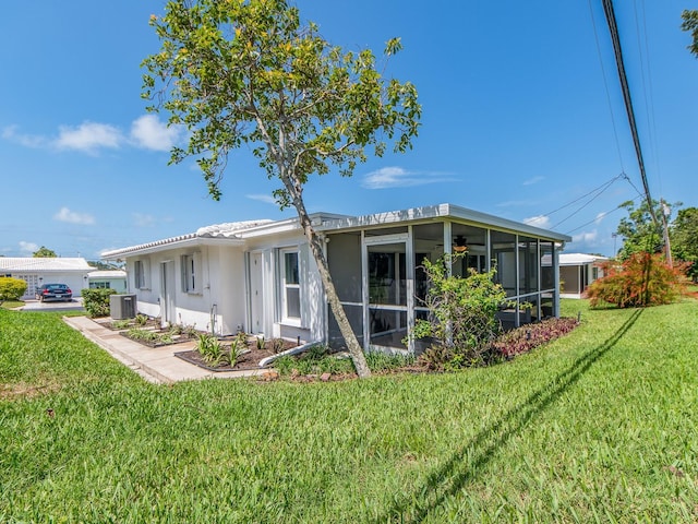 14045 90th Pl, Seminole, FL 33776 - back of property featuring a sunroom, a lawn, central AC unit, and stucco siding
