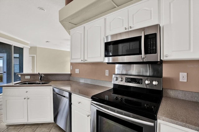 23917 Pow Wow Dr, Lutz, FL 33559 - kitchen featuring stainless steel appliances, a sink, a peninsula, white cabinetry, and light tile patterned floors