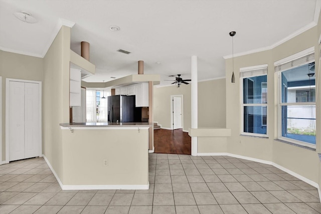 23917 Pow Wow Dr, Lutz, FL 33559 - kitchen featuring black fridge with ice dispenser, light tile patterned flooring, white cabinets, baseboards, and a peninsula