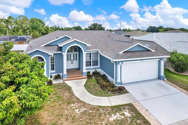 23917 Pow Wow Dr, Lutz, FL 33559 - ranch-style house with an attached garage, stucco siding, french doors, driveway, and roof with shingles