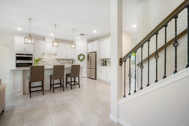 13157 Peachleaf Ave, Riverview, FL 33579 - kitchen with appliances with stainless steel finishes, tasteful backsplash, white cabinets, a breakfast bar area, and recessed lighting