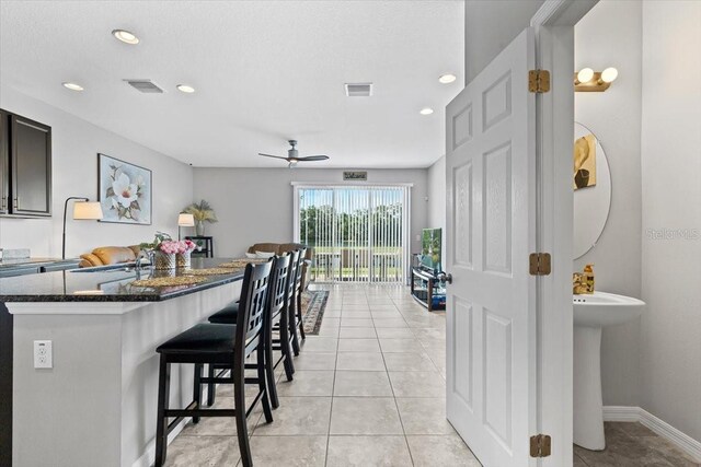 7916 Evergreen Creek Ct, Riverview, FL 33578 - kitchen with a kitchen island, a breakfast bar area, ceiling fan, dark stone countertops, and recessed lighting