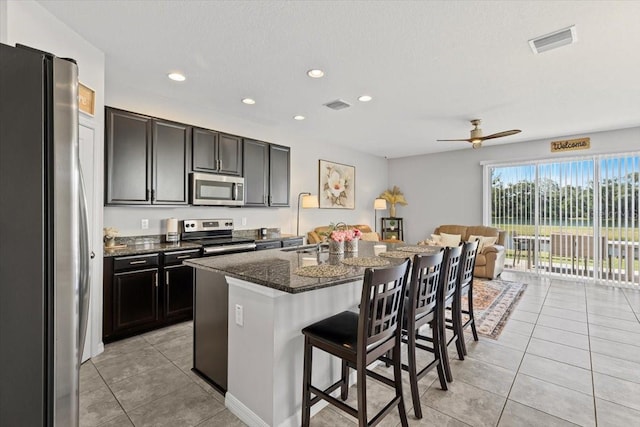7916 Evergreen Creek Ct, Riverview, FL 33578 - kitchen featuring appliances with stainless steel finishes, light tile patterned floors, a kitchen bar, recessed lighting, and a center island with sink