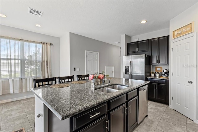 7916 Evergreen Creek Ct, Riverview, FL 33578 - kitchen with appliances with stainless steel finishes, light tile patterned flooring, an island with sink, dark stone counters, and recessed lighting