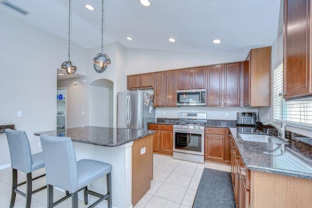 31349 Philmar Ln, Wesley Chapel, FL 33543 - kitchen with stainless steel appliances, a breakfast bar area, a center island, light tile patterned floors, and high vaulted ceiling