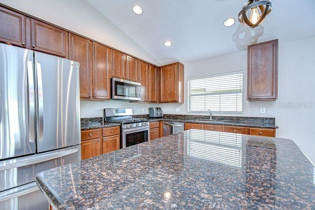 31349 Philmar Ln, Wesley Chapel, FL 33543 - kitchen featuring stainless steel appliances, recessed lighting, lofted ceiling, brown cabinetry, and dark stone counters
