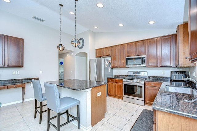 31349 Philmar Ln, Wesley Chapel, FL 33543 - kitchen with appliances with stainless steel finishes, light tile patterned flooring, a kitchen island, arched walkways, and a textured ceiling