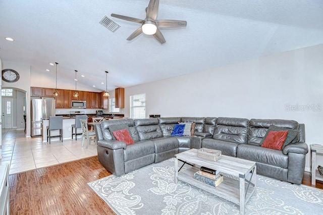 31349 Philmar Ln, Wesley Chapel, FL 33543 - living room featuring vaulted ceiling, a ceiling fan, arched walkways, and a textured ceiling